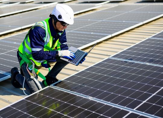 Engineer technician using laptop checking and operating system on rooftop of solar cell farm power plant, Renewable energy source for electricity and power, Solar cell maintenance concept