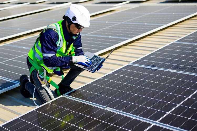 Engineer technician using laptop checking and operating system on rooftop of solar cell farm power plant, Renewable energy source for electricity and power, Solar cell maintenance concept